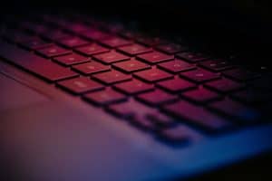 Close-up of a sleek, modern keyboard illuminated with pink and purple hues, showcasing advanced technology design by ELIME Tech for optimized user experience and digital innovation.