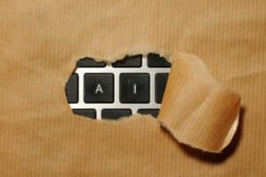 Close-up of a torn paper revealing a keyboard with "AI" keys, symbolizing AI audit and analysis.