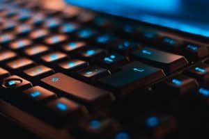 Close-up view of a backlit black computer keyboard with blue LED lighting, emphasizing modern technology and digital communication. Perfect for highlighting IT innovation and tech solutions.